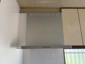 クリナップ製深型レンジフードW600（シルバー）が壁面に設置され、上部には白いパネルで造作された空きスペースが整然と仕上がっている