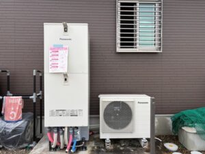 新設されたPanasonic エコキュートSシリーズ本体と室外機。白い本体に取扱説明書が貼られ、配管は樹脂置台の下に整然と収められています