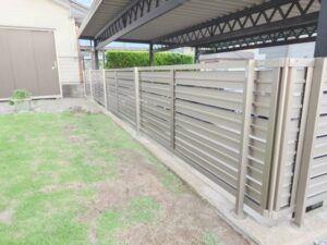 完成後の庭側全景。フェンスと手摺が塀の上に並び、芝生と砂利敷きの境界も整えられ、庭まわりの使い勝手が向上しました。