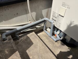 新設エコキュート下部の配管接続部。新規配管が整然と配置され、保温材で覆われています