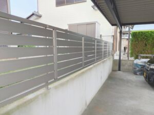 完成したフェンスの全景。LIXILフェンスAB YS3型が塀の上に連続して設置され、横スリットのデザインが庭側の視線を遮ります。
