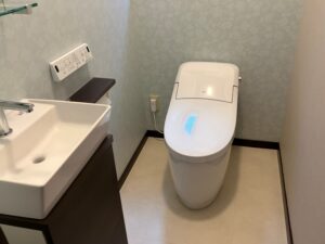 完成後のトイレ全景。LIXIL プレアスLSとキャパシアが設置され、グレー系のクロスと明るい床材で統一されています