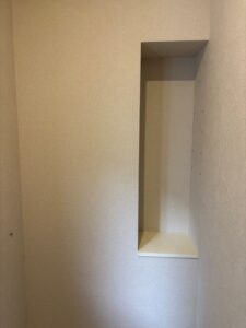 1階トイレの埋め込み収納ニッチ。白い内装で仕上げられ、奥行きのある棚板が水平に取り付けられています